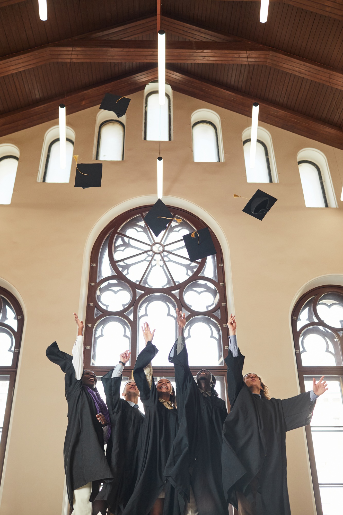 Graduates throwing caps in air indoors